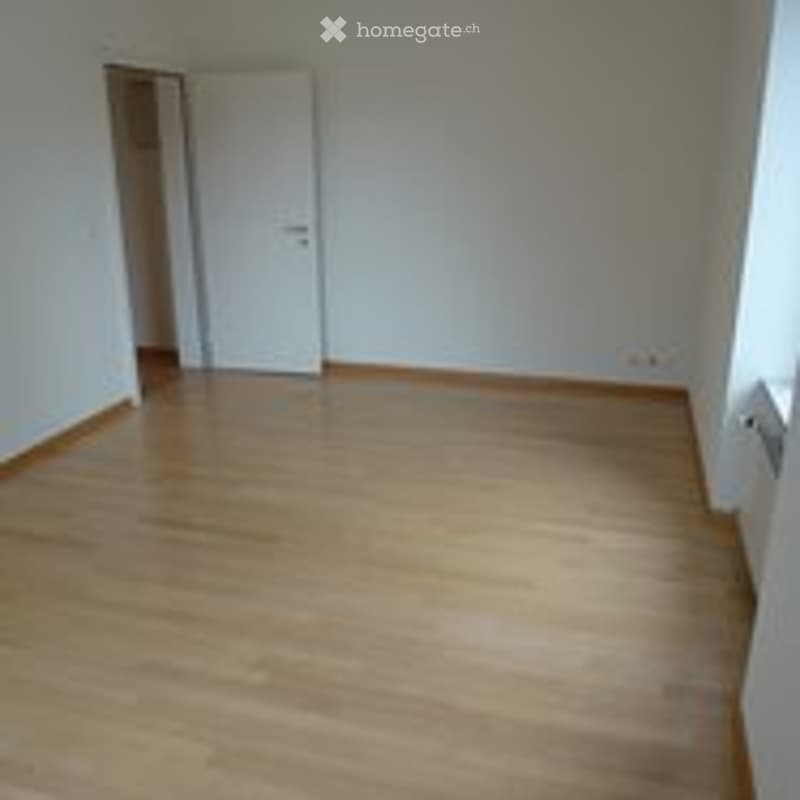 Completely empty room with light wooden flooring and white walls. No furniture or equipment.
