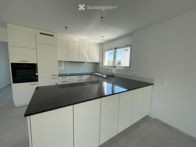 Modern kitchen with white cabinets, black granite countertops, and a built-in oven.