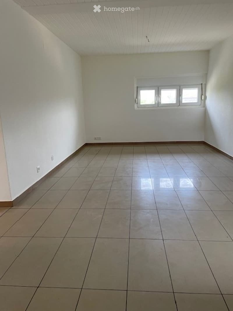 Empty room with tiled floor and white walls, featuring a single window with three panes and basic electrical outlets.