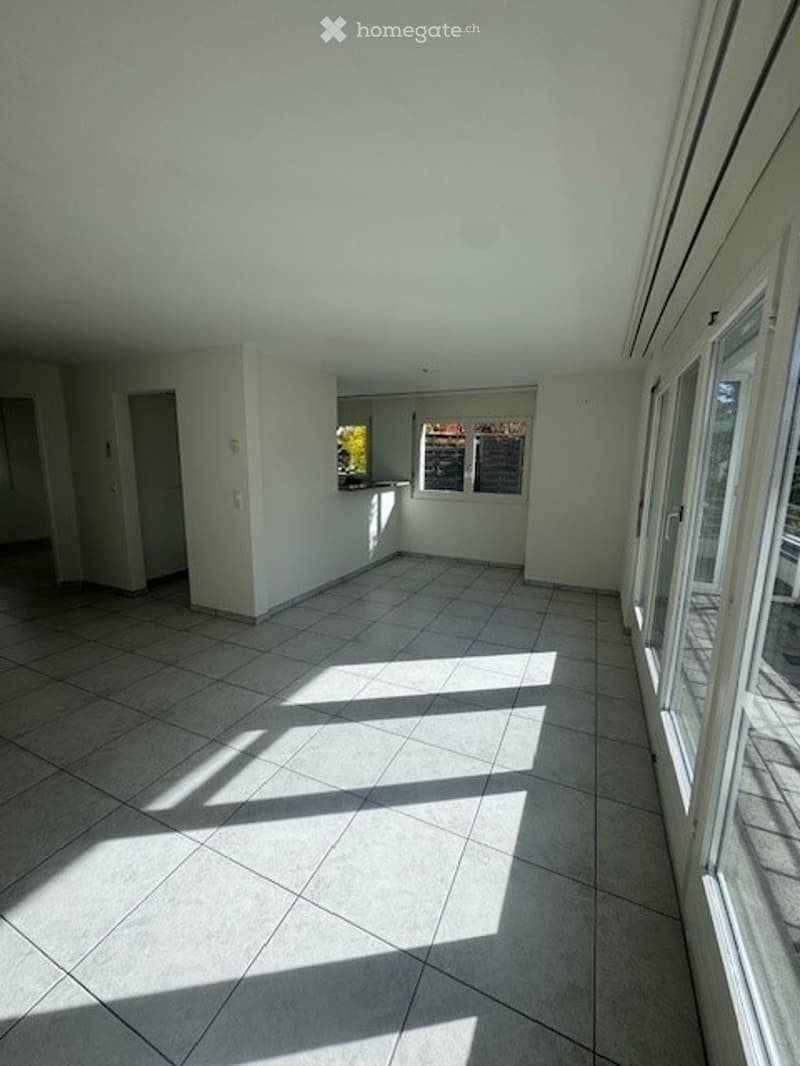 empty room with white tiled floor, white walls, sliding doors leading to a balcony, small window