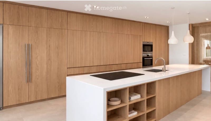 Modern kitchen with light wood cabinets, white countertops, built-in microwave and oven, induction cooktop, and pendant lights.