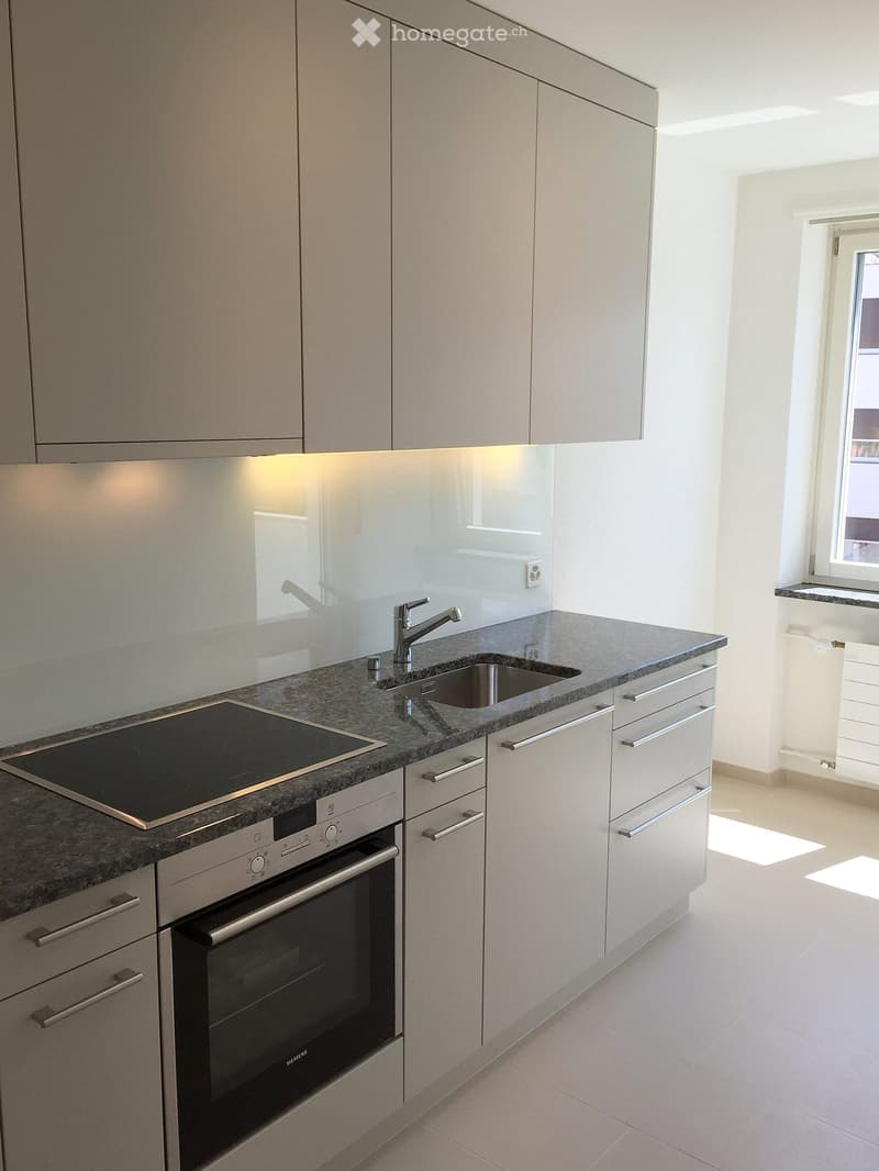 modern kitchen with white cabinets, granite countertop, induction stove, oven, sink, faucet, white tiles