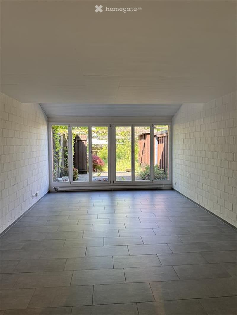 Unfurnished Room. Empty room with white brick walls, tiled floor, and large glass doors leading to an outdoor area.