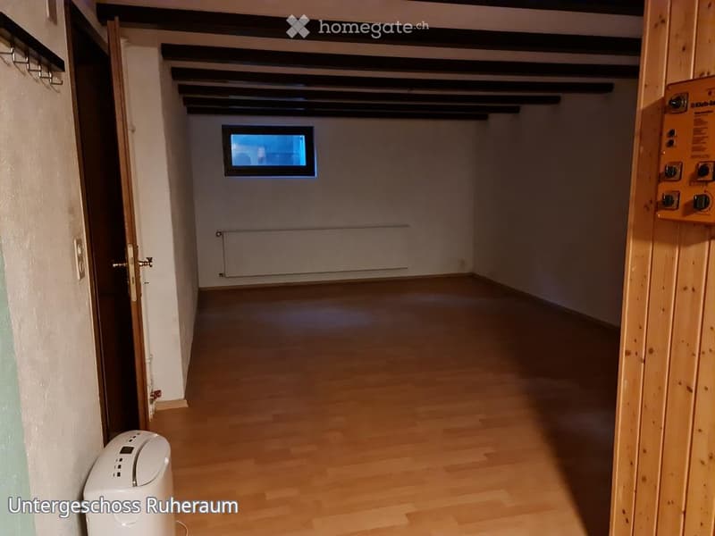 Empty hallway with wooden flooring, white walls, and a small window at the far end. No furniture or equipment visible.