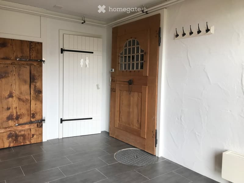 Entrance hall with wooden doors, tiled floor, white walls, coat hooks, radiator