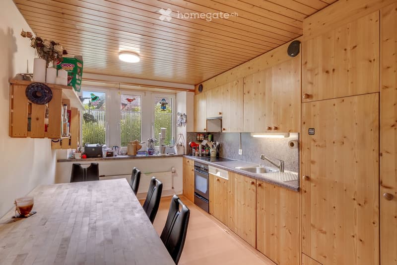 Bright kitchen with wooden cabinets, a dining table with chairs, and various appliances including an oven and sink.
