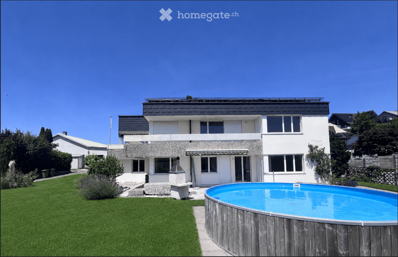 Modern two-story house with white exterior, large windows, and a swimming pool in the front yard.