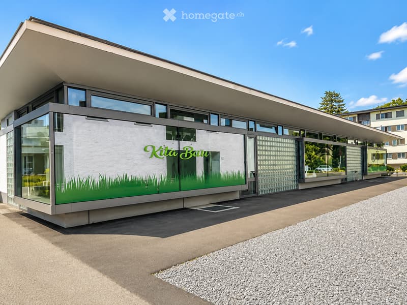 Modern building with large glass windows and a flat roof, featuring a green graphic design on the facade.