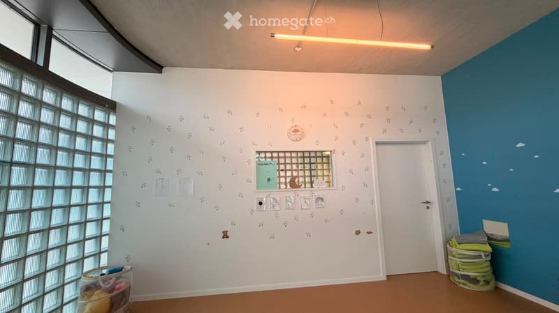 Bright room with white and blue walls, large window with frosted glass, decorative wall decals, storage bins, and a laundry basket.
