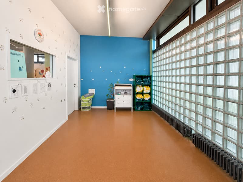 Bright hallway with white and blue walls, a clock, a small potted plant, and storage shelves with folded items.