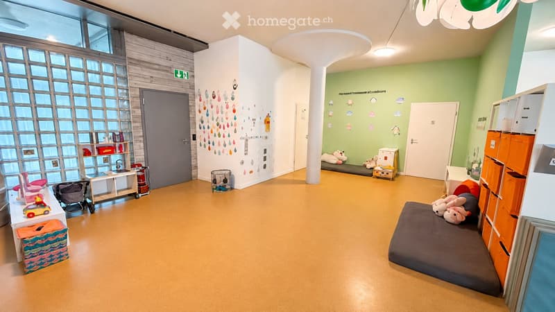 Bright, colorful children's room with a low bed, storage units, shelves, and various toys including a toy car, toy box, and a stroller. The room features a large window with a grid pattern and playful wall decorations.