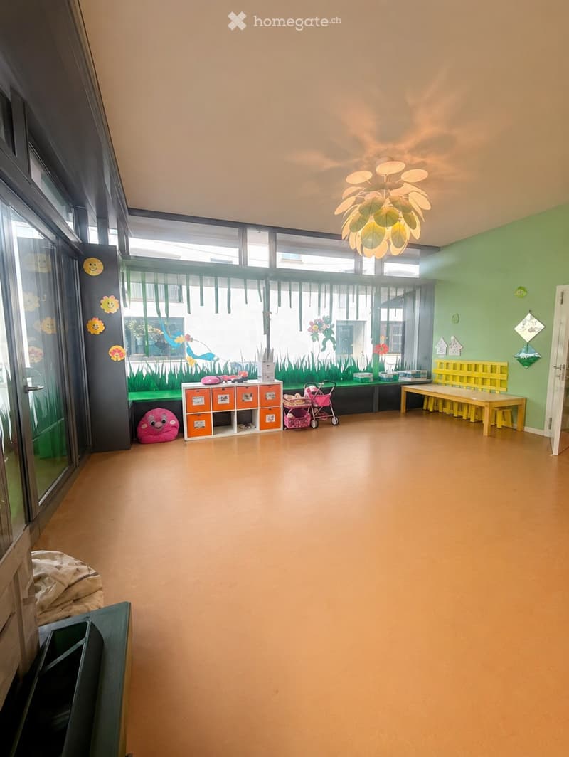 Brightly colored children's play area with a storage unit, bench, table, stool, toy stroller, and plush toy.