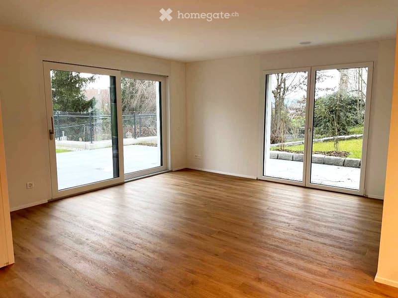 Empty room with wooden flooring and large sliding glass doors leading to an outdoor area.
