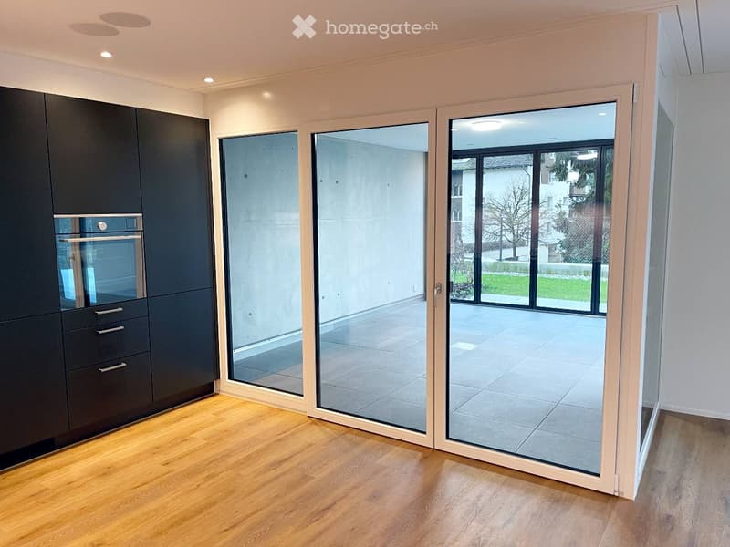 Modern kitchen with dark grey cabinets, a built-in oven, and large glass sliding doors leading to a patio.