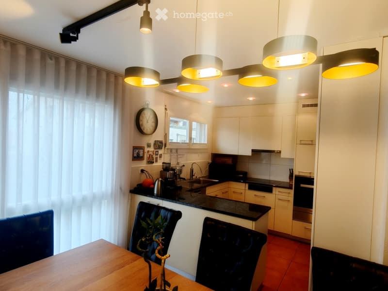 modern kitchen with island, black countertops, stainless steel appliances, white cabinetry, hanging ceiling lights