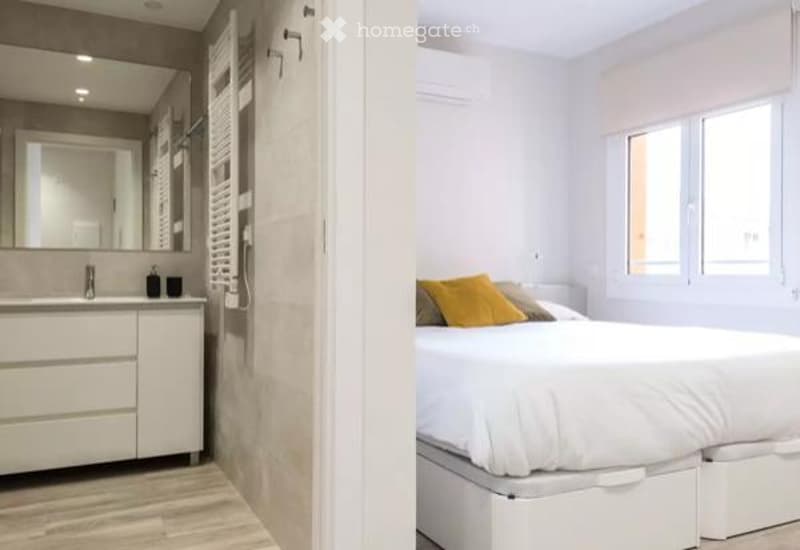 Modern bedroom with a white bed, yellow pillows, and a sleek bathroom area featuring a mirror and sink.