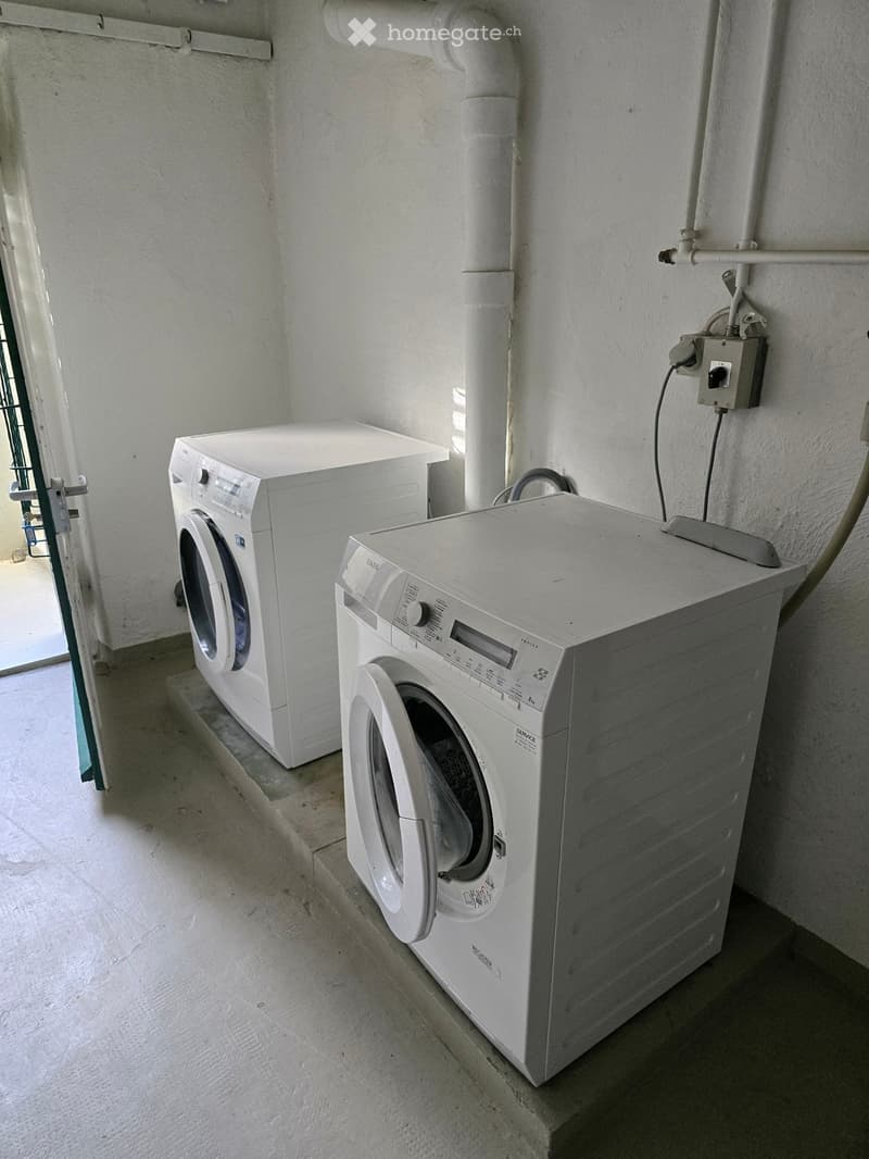 A small utility room with a washing machine and a dishwasher placed side by side against a wall.