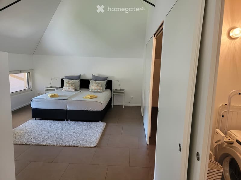 Modern bedroom with a double bed, nightstands, lamps, and a white rug on the floor.