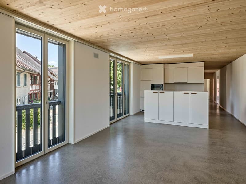 Open-plan space with white cabinets, a microwave, and large glass doors leading to a balcony.
