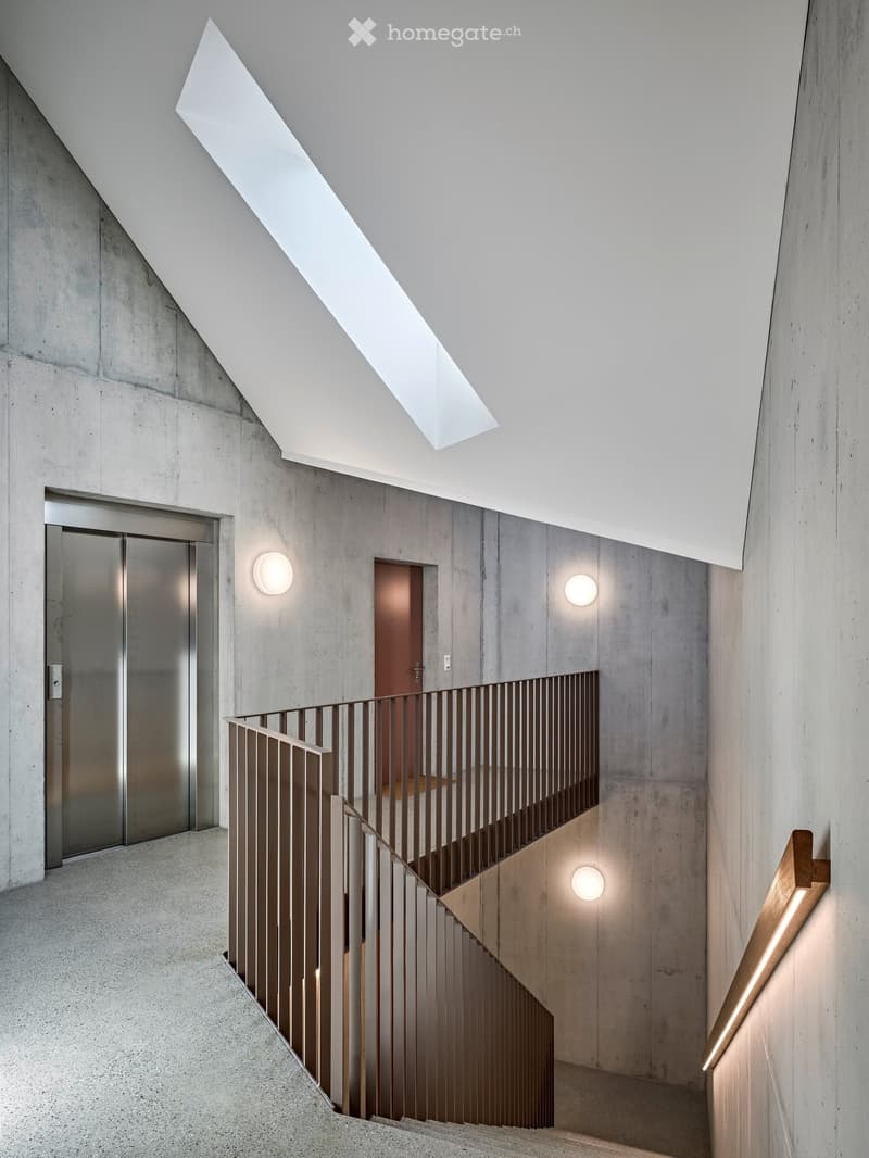 Modern interior staircase with concrete walls, sleek metal railing, and integrated lighting fixtures.