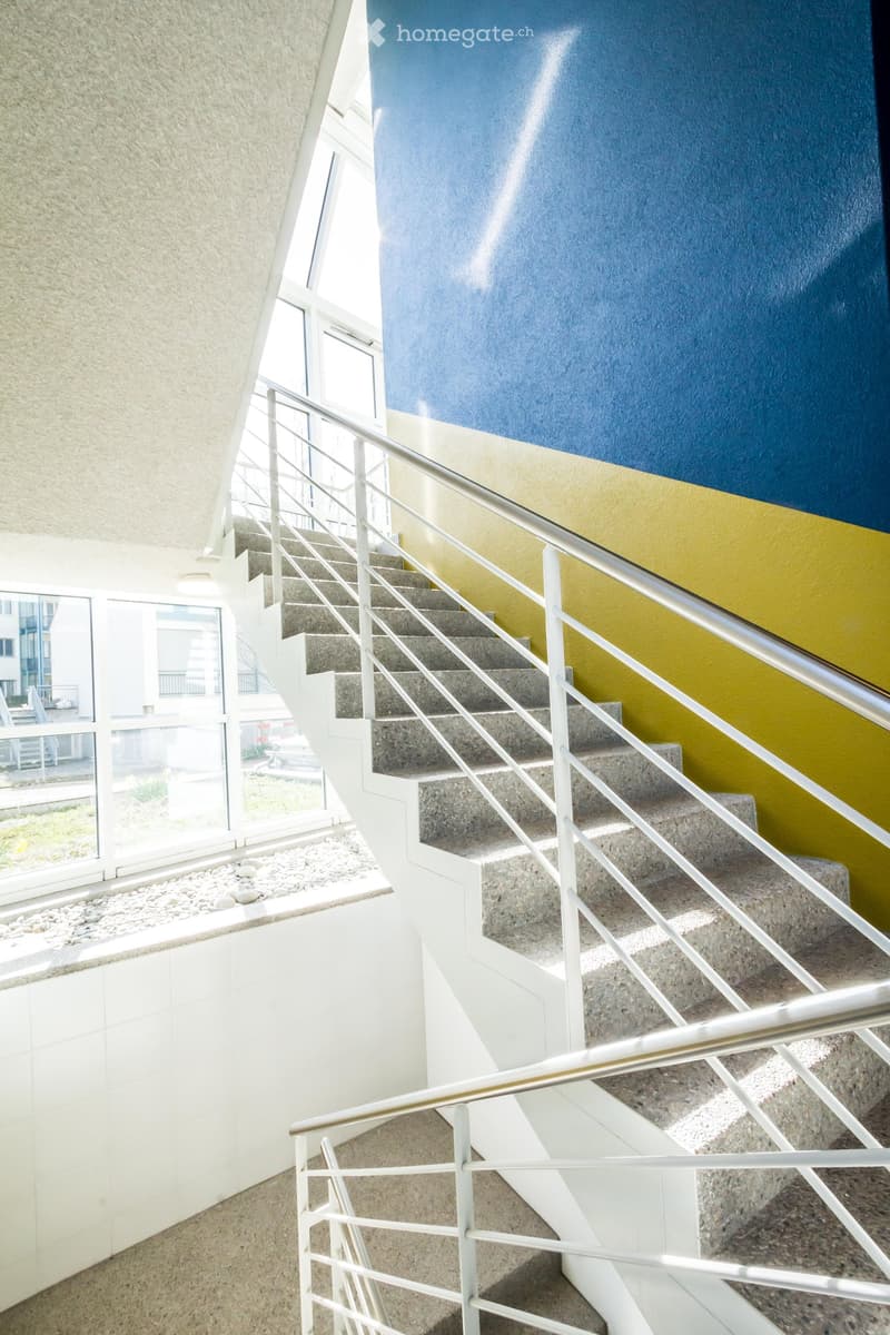 Stairwell with white tiles, yellow wall, white handrail