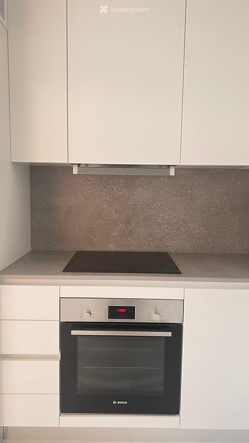 Modern kitchen with white cabinets, a Bosch oven, and an induction stove, featuring a sleek, minimalist design.