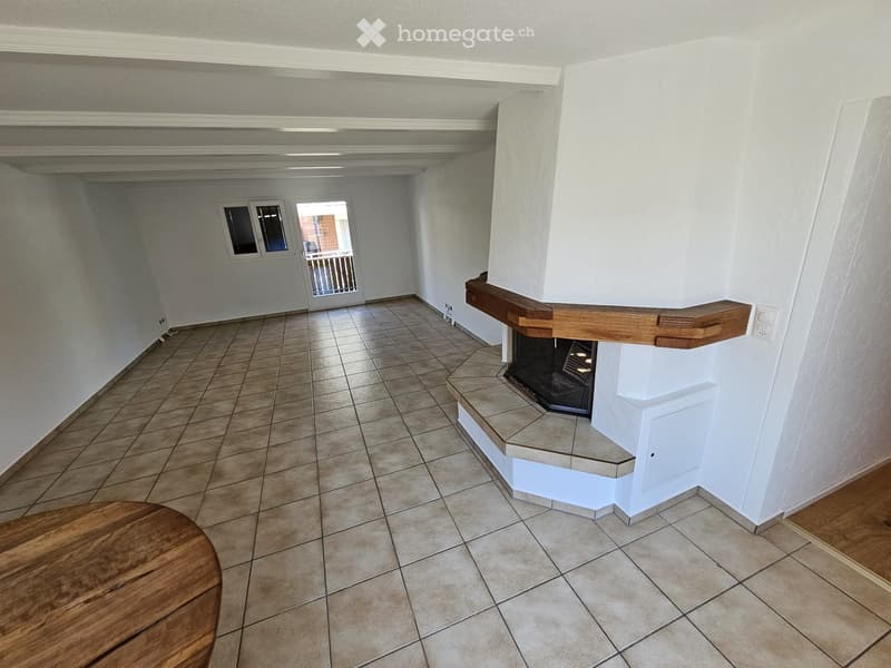 Empty room with tiled floor, fireplace, and a wooden table in the foreground.