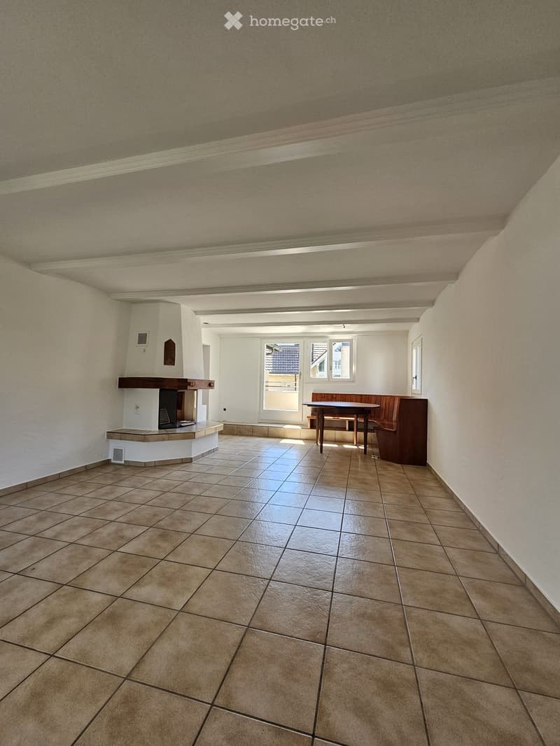 Bright room with tiled floor, fireplace, bench, and table near windows.