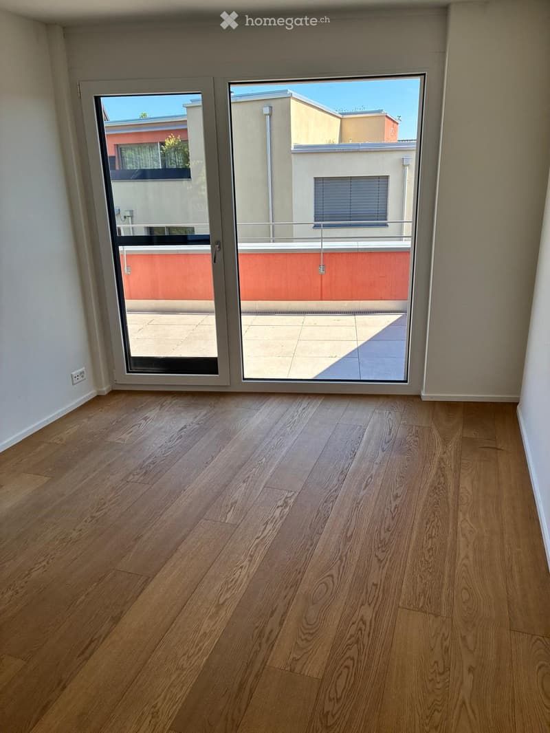 Empty room with wooden flooring and large sliding glass doors leading to a balcony or terrace area.