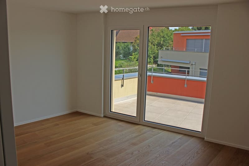 Empty room with wooden flooring and large sliding glass doors leading to a balcony or terrace area.
