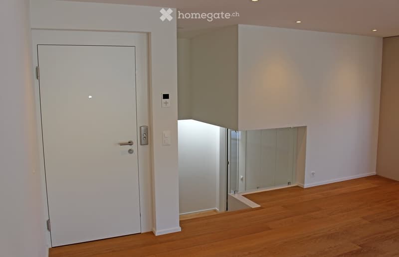 Empty room with wooden flooring, white walls, and a white door leading to another space. No furniture or equipment is visible.