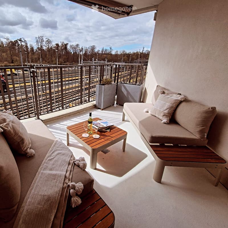 Balcony with two sofas, a wooden coffee table, wine bottle, wine glasses, and potted plants.
