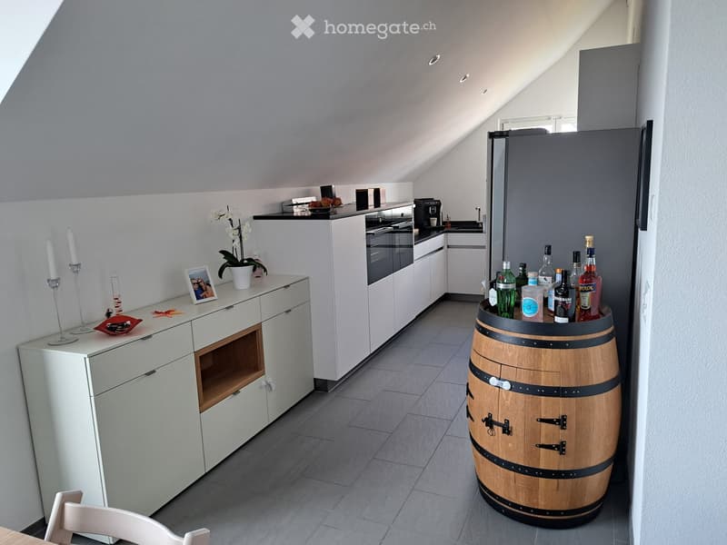 Modern kitchen with white cabinets, stainless steel appliances, a barrel used as a bar, and decorative items including candles, a picture frame, and a flower pot.