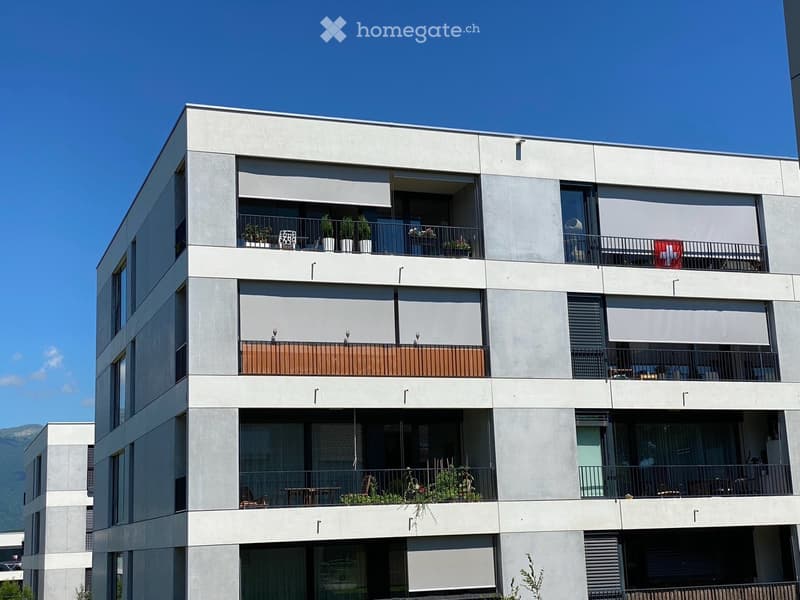 Modern multi-story apartment building with balconies, large windows, and contemporary design.