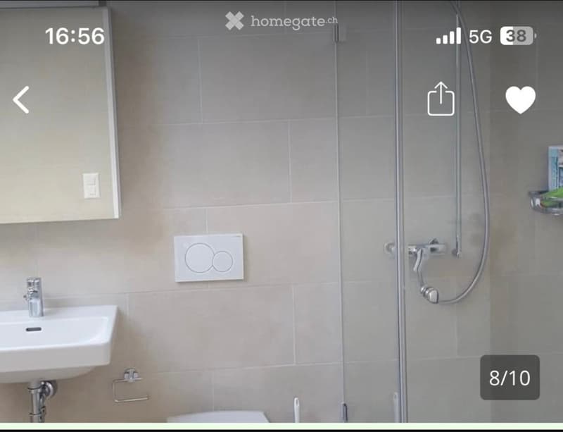 Modern bathroom with a white sink, chrome faucet, glass shower enclosure, and a towel rack. Light beige tiles and sleek fixtures.