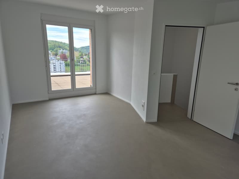 Empty room with light grey carpet, white walls, large sliding glass door leading to a balcony, and a closed door to another room.