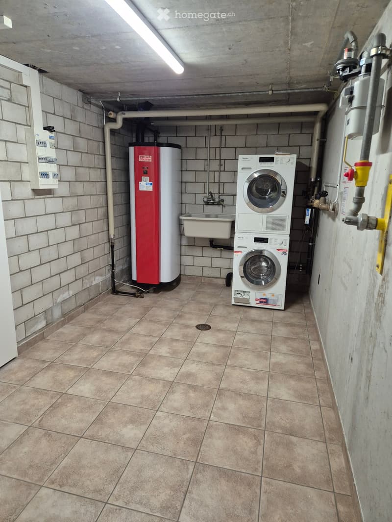 Utility room with tiled floor, brick walls, washing machine, water heater, and sink.