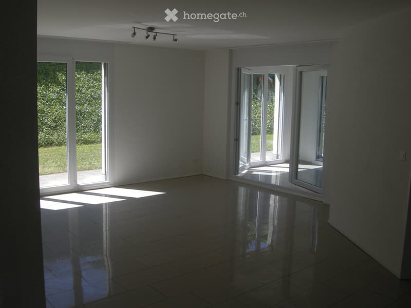 Empty room with large windows and sliding doors leading to an outdoor area, polished tile floor, and recessed lighting.