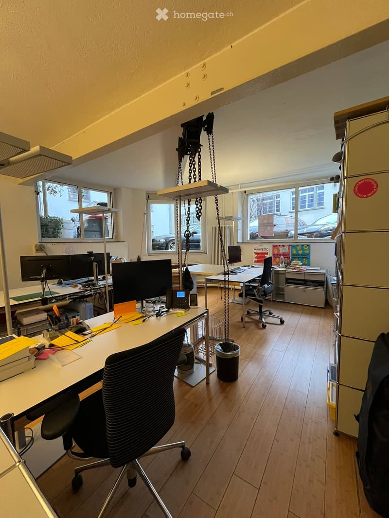 A room with multiple desks, office chairs, multiple monitors and a radiator.