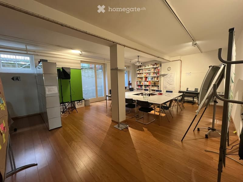 large open room with hardwood floors, large windows, desk, chairs, bookcase, projector, whiteboards