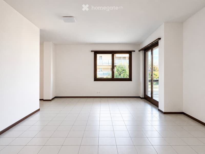 Empty room with white tiled floor, white walls, and large windows with wooden frames. No furniture or equipment present.