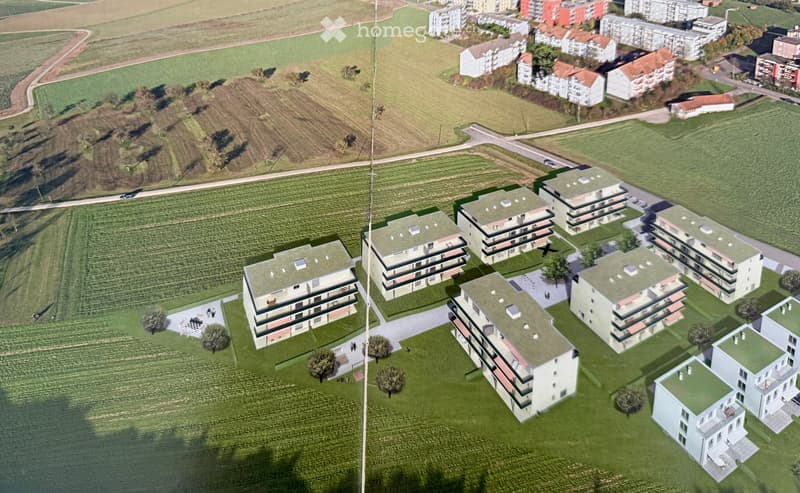 Aerial view of a residential complex with multiple apartment buildings, surrounded by green spaces and open fields.
