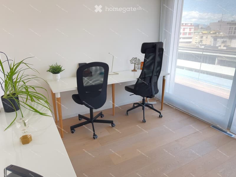 Modern office space with a white desk, ergonomic chairs, potted plants, and a city view through large windows.