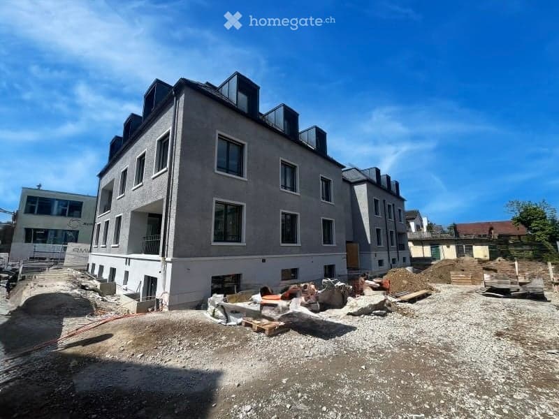Building. Modern multi-story building under construction with large windows and balconies, surrounded by construction materials and debris.