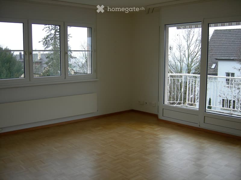 Empty room with wooden flooring, large windows, and a balcony with white railing.