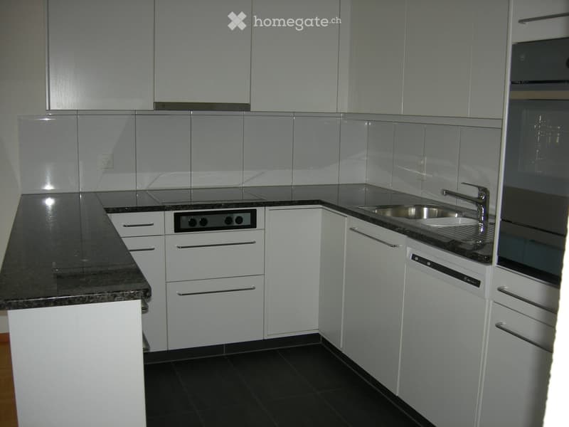Modern kitchen with white cabinets, granite countertops, stainless steel sink, and built-in appliances.