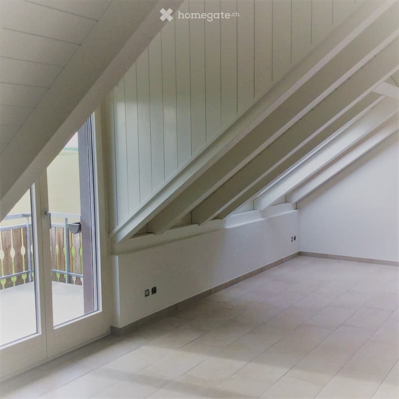Empty room with tiled floor, white walls, and large windows, featuring a wooden ceiling with exposed beams.
