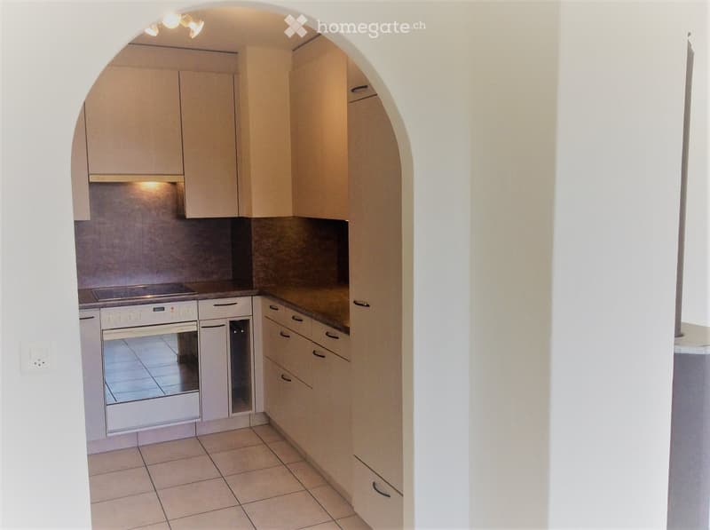 Modern kitchen with white cabinets, a built-in oven, and a tiled floor. The space features a clean, minimalist design with a visible countertop and storage cabinets.