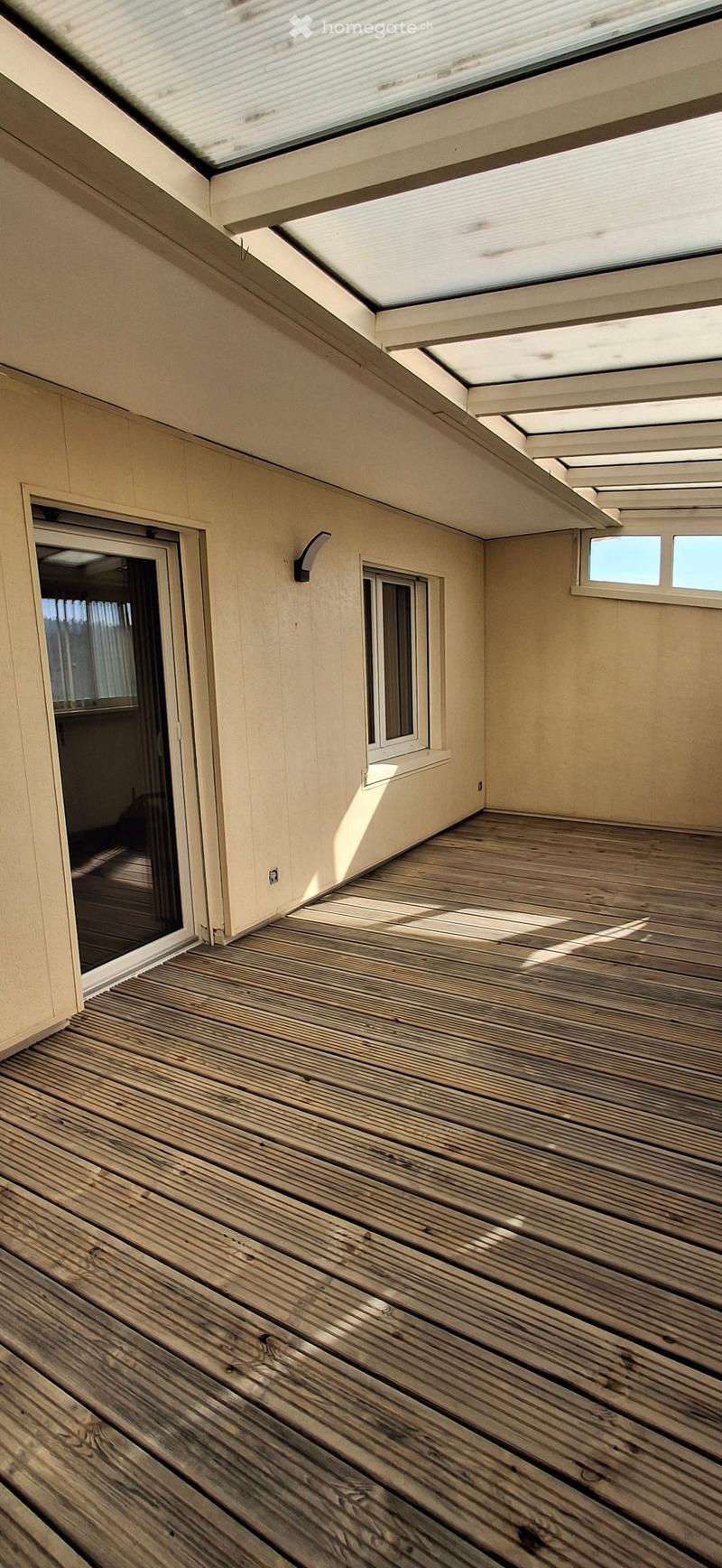 Wooden deck with skylight windows, sliding glass door, and small windows on the side.