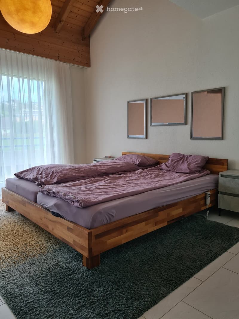 Cozy bedroom with a wooden bed, purple bedding, nightstands, and mirrors on the wall.
